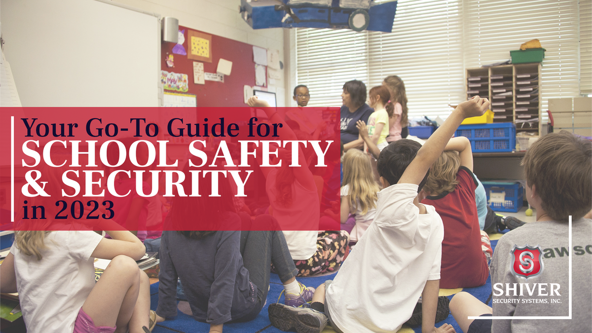 Children sitting in a classroom with their hands raised next to the text "your go-to-guide for school safety & security in 2023